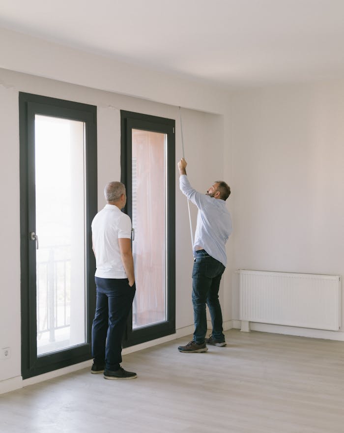 Crafting Captivating Headlines: Your awesome post title goes here Two men measuring window dimensions in a bright Istanbul apartment.